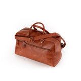 The Leather Duffle Bag Regent by Vintage Leather Sydney features brown leather, gold hardware, two handles, an adjustable shoulder strap, and a front zippered pocket, shown on a white background.