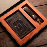 The Leather Gift Box With Credit Card Wallet & Keyring by Vintage Leather Sydney features a brown wallet and matching keyring with gold hardware, elegantly presented in an orange-lined leather box on a wooden surface.