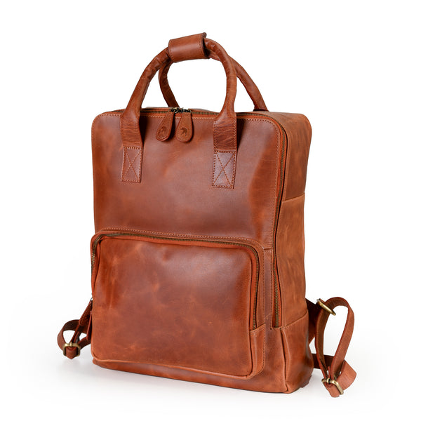The Bolton Leather Backpack – Tan Brown from Vintage Leather Sydney, featuring two short handles, adjustable shoulder straps, and a large front zip pocket, is displayed in a stylish container with smooth lines against a white background.