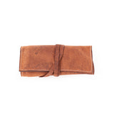 The Leather Artist Roll Zip by Vintage Leather Sydney is a brown leather pouch with visible stitching, neatly rolled and secured with a matching leather strap.